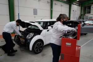 Auto eléctrico blanco Olinia con dos operadores mexicanos en el proceso de ensamblaje.