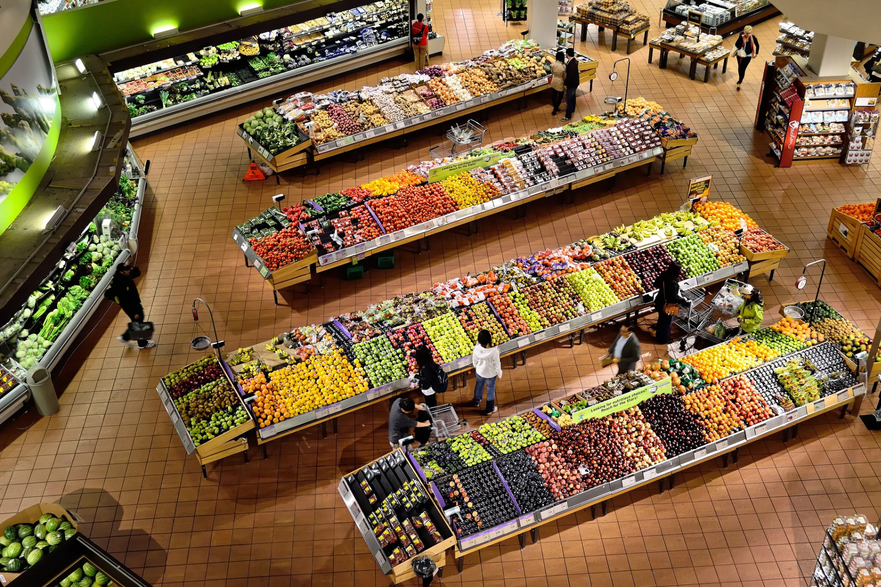 Vista de un supermercado con frutas y verduras organizadas en estantes, reflejando cambios en los precios de consumo.