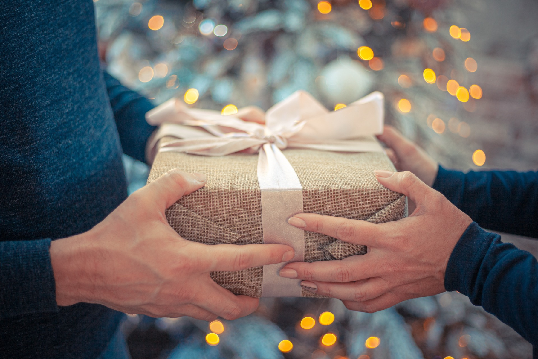 Pareja intercambiando un regalo de Navidad, representando el espíritu festivo y los gastos asociados.