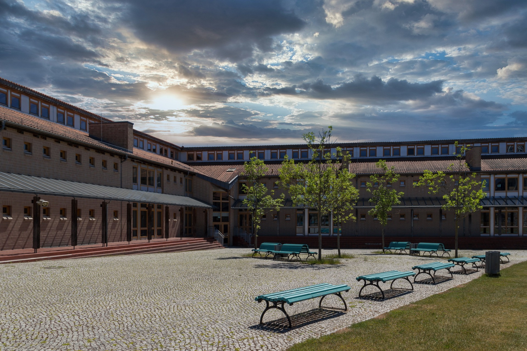 Edificio escolar con patio amplio y bancas, representando el compromiso del gobierno mexicano con la educación media superior mediante nuevas construcciones y ampliaciones.