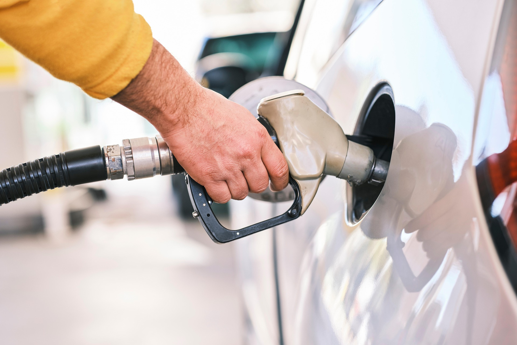 Hombre repostando combustible en una gasolinera, llenando el tanque de su automóvil para ilustrar los estímulos fiscales.