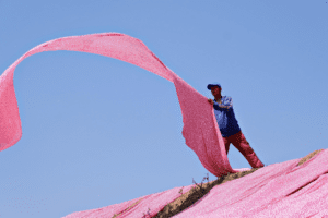 Un hombre extiende una tela en una fábrica textil, representando la producción y abastecimiento de materiales en la industria de confección dentro de la Alianza del Pacífico.