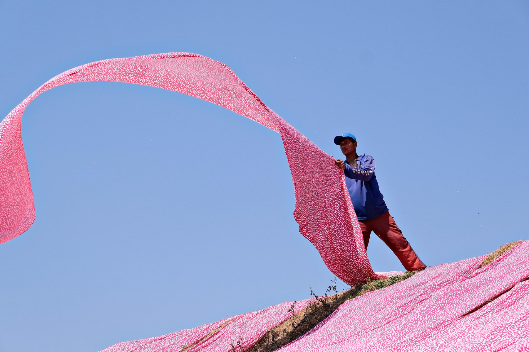 Un hombre extiende una tela en una fábrica textil, representando la producción y abastecimiento de materiales en la industria de confección dentro de la Alianza del Pacífico.