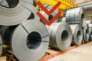 Ruedas de acero en el interior de una fábrica con una flecha roja apuntando hacia abajo, simbolizando la caída en exportaciones.