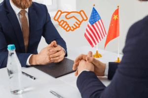 Dos representantes de Estados Unidos y China estrechan la mano en una mesa de negociación, con las banderas de ambos países al fondo y un ícono de acuerdo resaltando el entendimiento alcanzado.