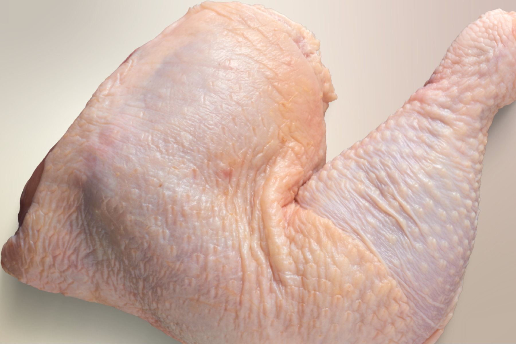 Fotografía de un pedazo de pollo crudo sobre una tabla de cocina, representando el producto avícola cuya importación ha sido suspendida por México debido a un brote de gripe aviar H5N1 en Brasil.