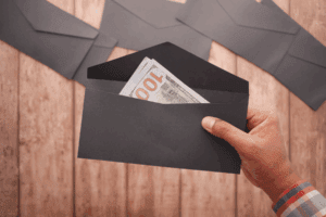 Mano sosteniendo un sobre con billetes de dólar, simbolizando el envío de remesas desde Estados Unidos a México