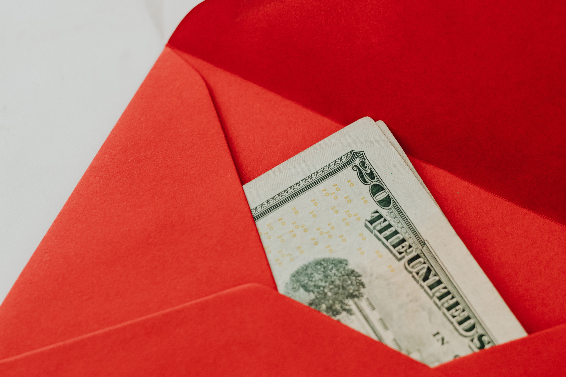 Gráfico de billetes de dólar sobre un fondo rojo con señales de alerta, simbolizando el impacto económico de un nuevo impuesto en EE. UU. sobre las remesas enviadas a México.