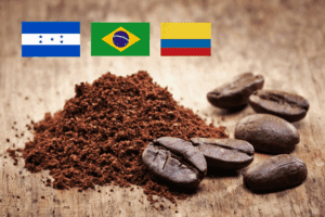 Banderas de Colombia, Honduras y Brasil junto a granos de café y una taza humeante en primer plano